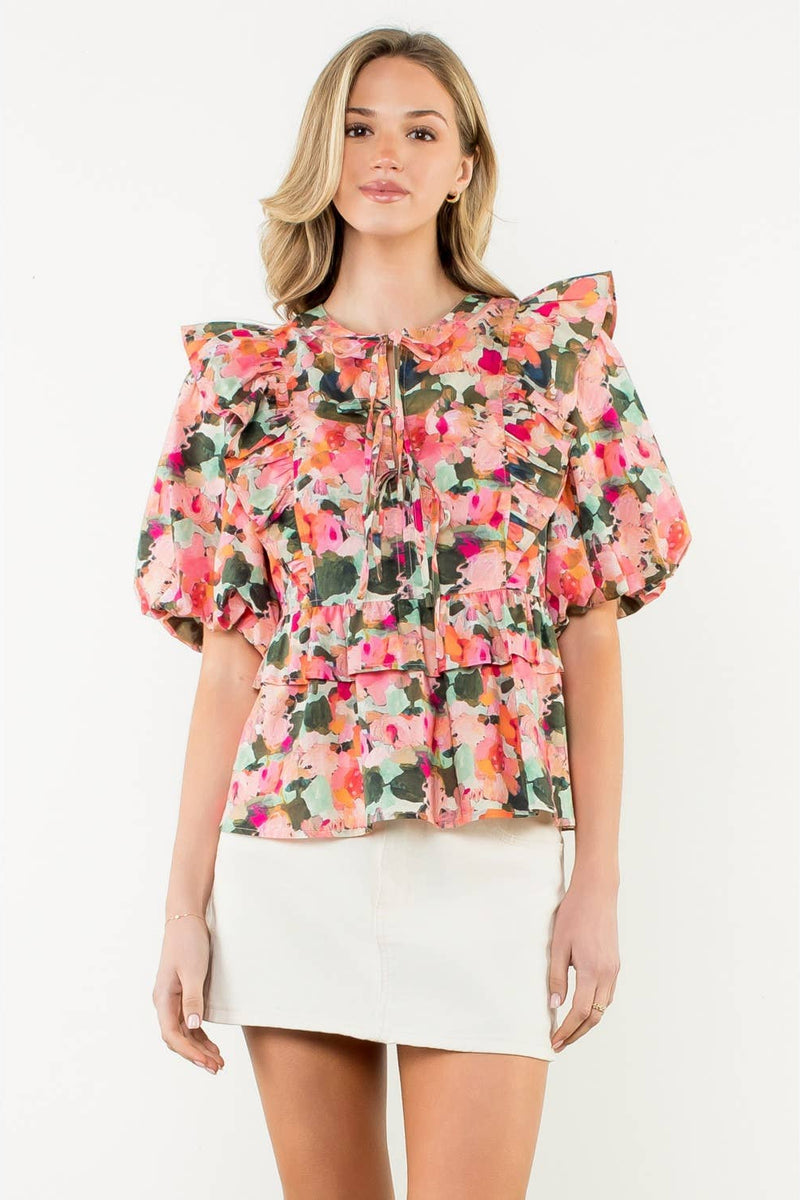 Woman wearing a floral blouse with ruffled sleeves on a white background