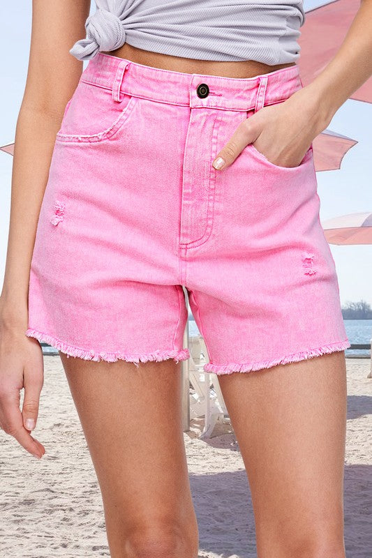 Person wearing pink denim shorts on a beach.
