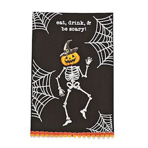 Cotton Halloween tea towel printed with a skeleton wearing a jack-o'-lantern head and mini pom trim