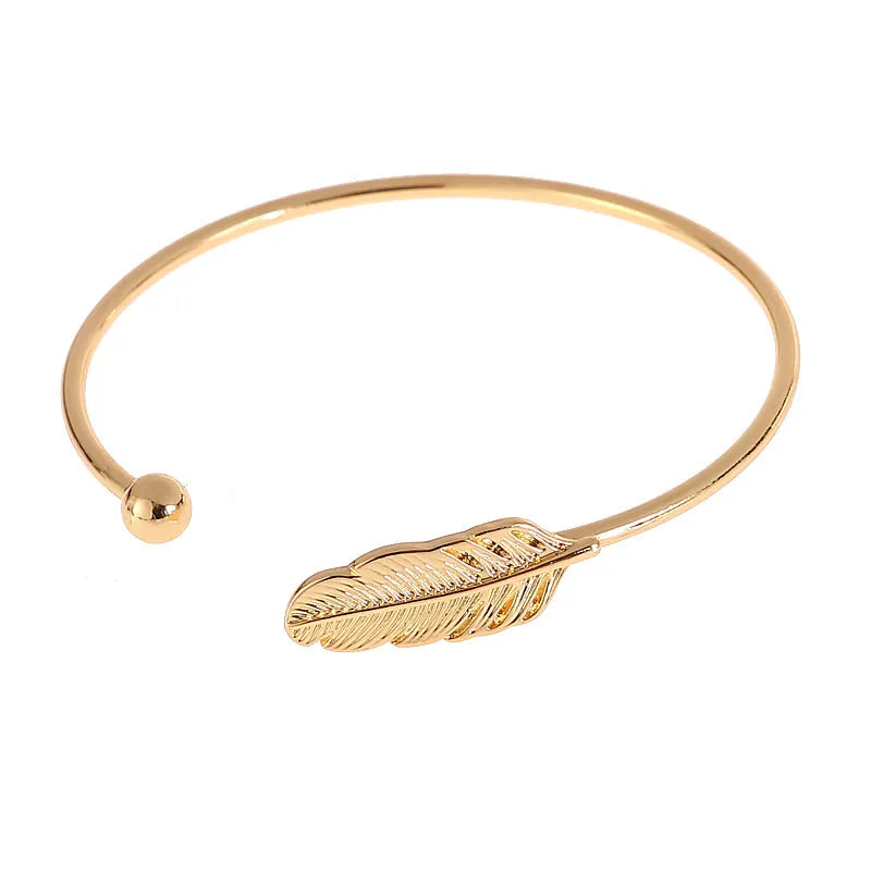 Gold feather open cuff bracelet with leaf design and polished round bead detail