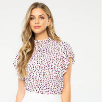 Woman wearing a patterned top and white shorts on a white background