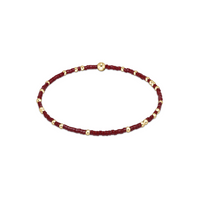 Bracelet with wine red beads and gold accents on a white background
