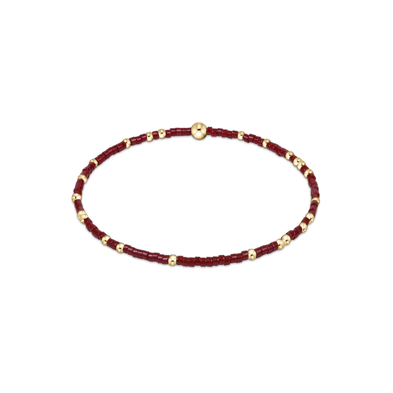 Bracelet with wine red beads and gold accents on a white background
