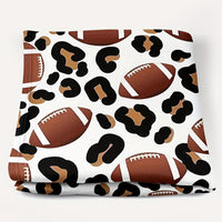 Patterned fabric with footballs and leopard print on a white background