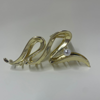 Gold hair clip with a pearl on a white background