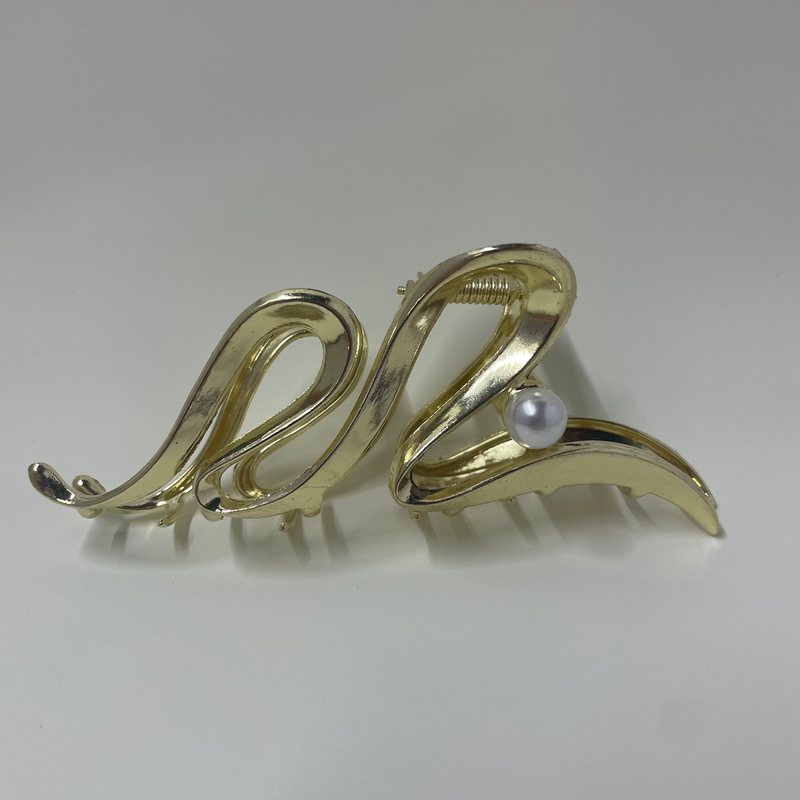 Gold hair clip with a pearl on a white background