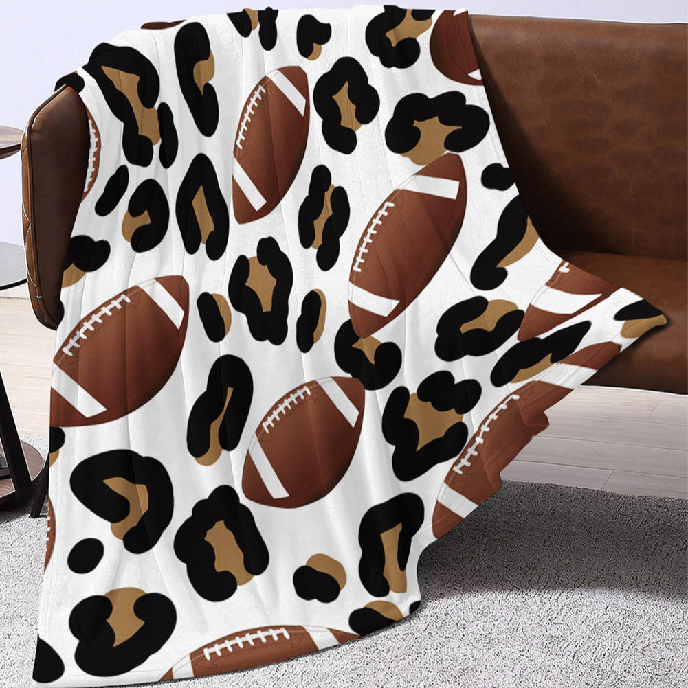 Leopard print blanket with football design draped over a brown chair.