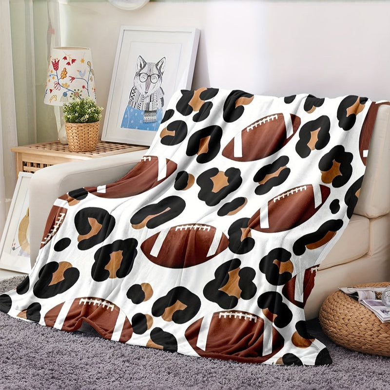 Leopard print blanket with football pattern draped over a couch in a living room.