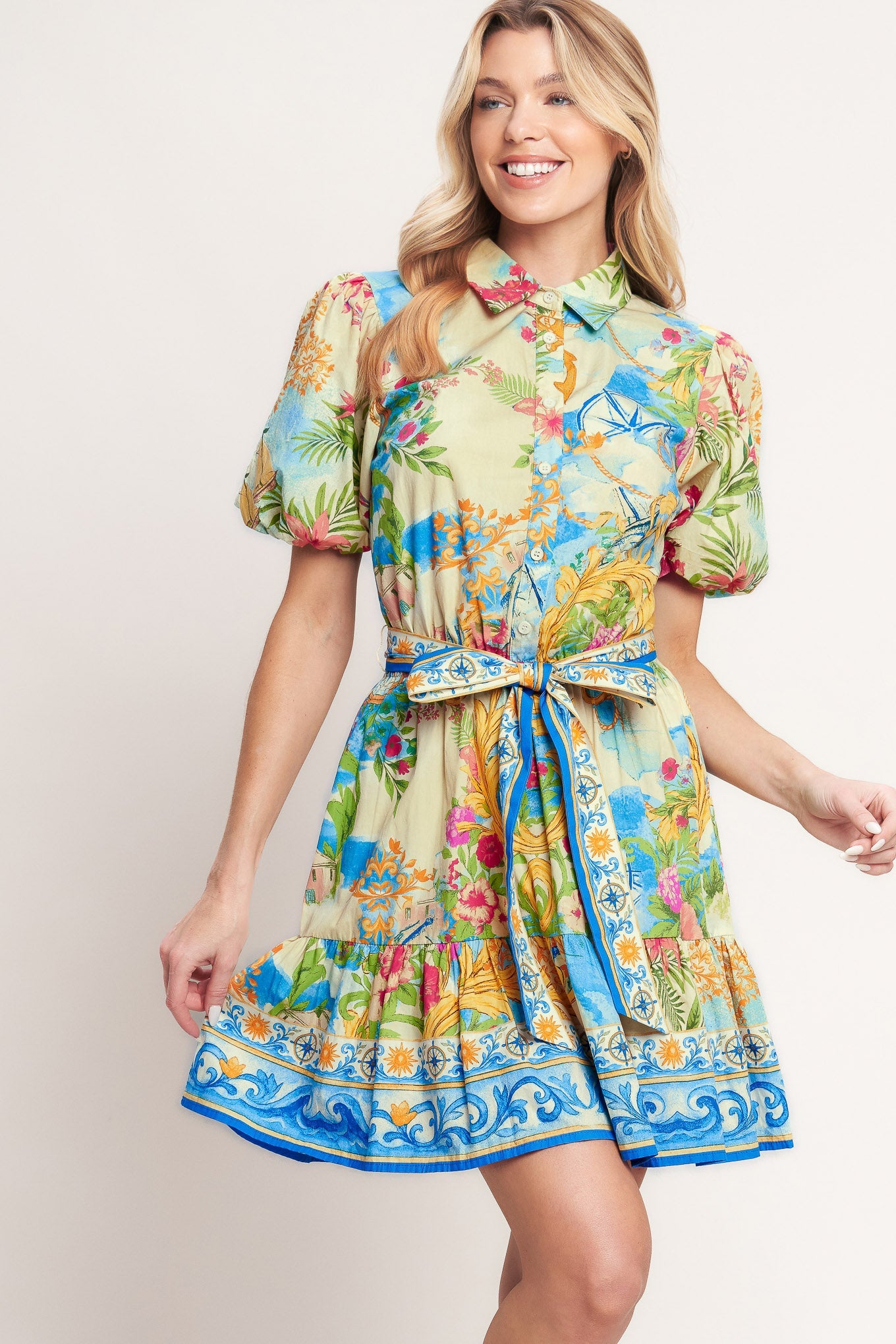 Woman wearing a colorful floral dress with a belt on a plain background