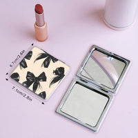 Open double-sided folding makeup mirror with black bow pattern and silver frame
