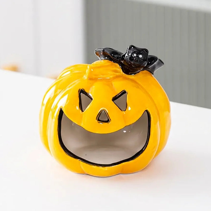 Orange ceramic pumpkin Halloween candle holder with a black bat detail and tealight glow