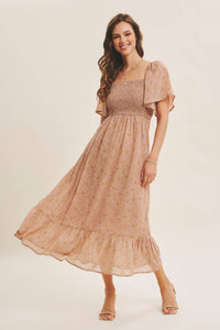 A woman wearing a beige floral printed square neck midi dress with smocked bodice and flutter sleeves.