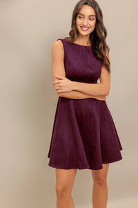 woman wearing a burgundy dress with her arms crossed smiling.
