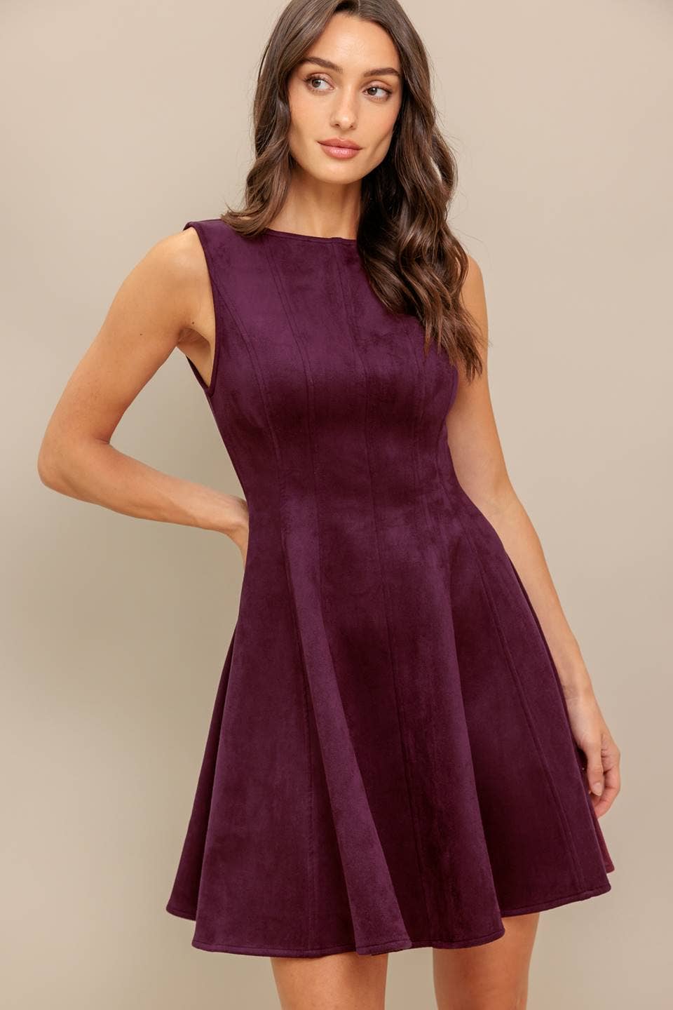 Woman wearing a suede purple dress with one hand on her hip