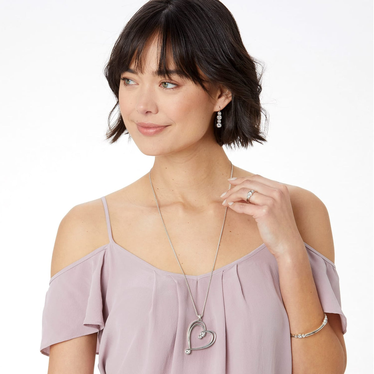 Model wearing a Brighton silver-plated heart pendant necklace with coordinating Brighton earrings, ring, and bracelet accessories