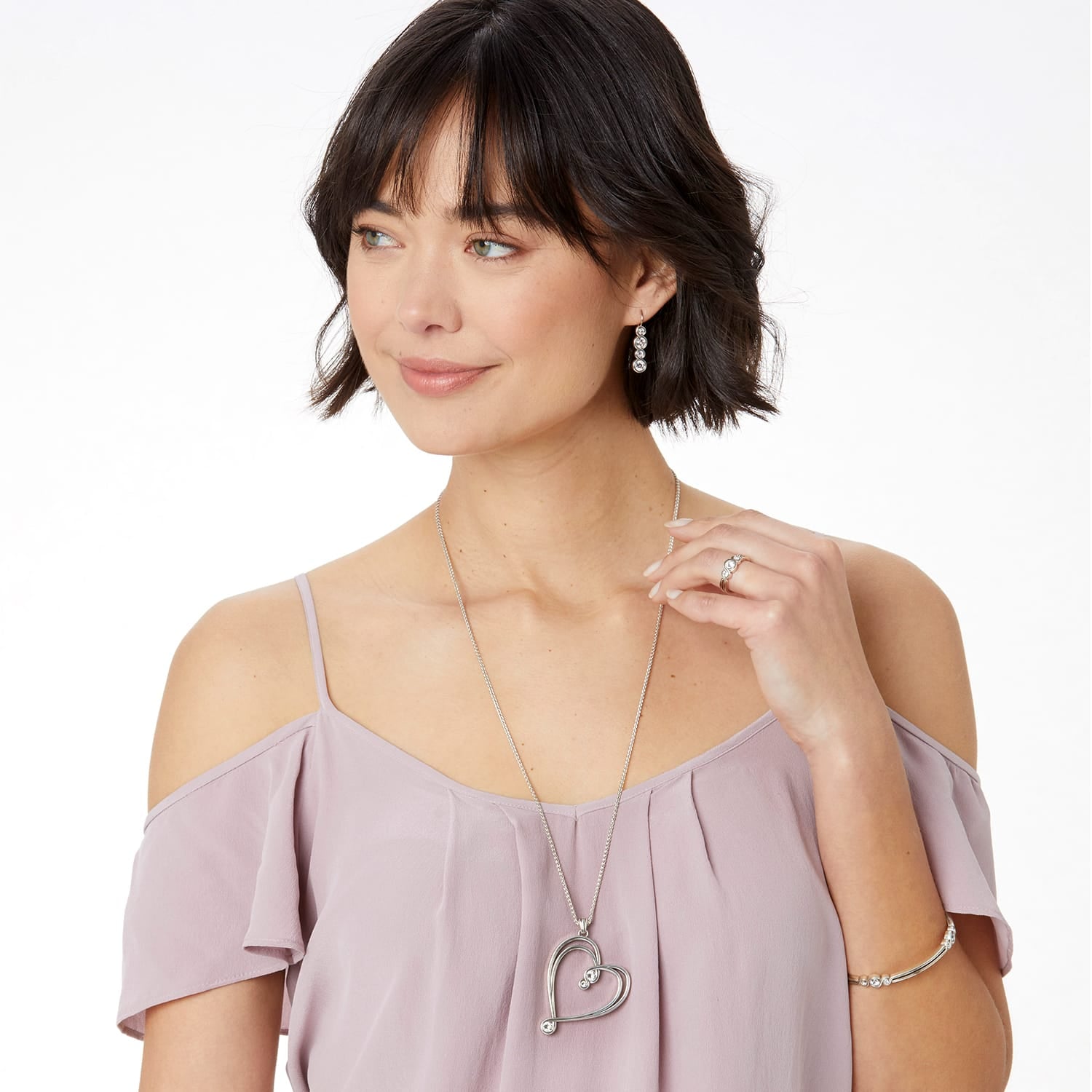 Model wearing a Brighton silver-plated heart pendant necklace with coordinating Brighton earrings, ring, and bracelet accessories