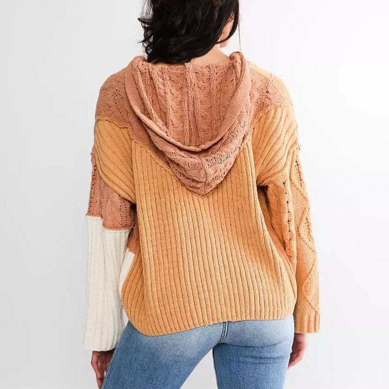 Person wearing a mustard yellow and brown ribbed knit hoodie on a white background